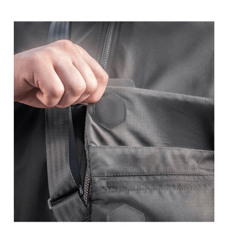 Hånd åpner lomme på M-Tac Konvert Taske Elite i holdbart Cordura-materiale med magnetisk åpning.