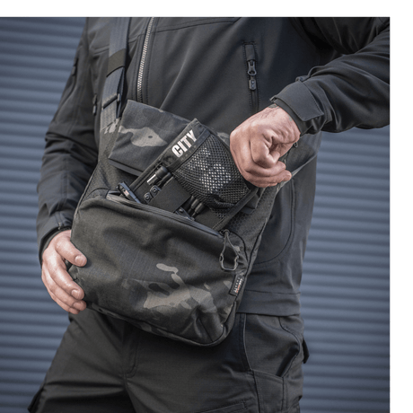 M-Tac Konvert Taske Elite i bruk, laget av slitesterkt Cordura-materiale, med justerbar skulderrem og hurtig tilgangs magnetlukning.