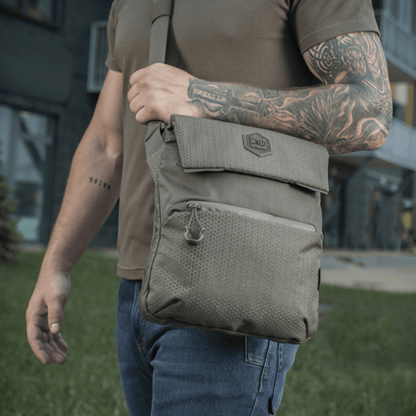 M-Tac Konvert Taske Elite båret av en person ute, laget av slitesterk Cordura 500D og Cordura Hex 1000D, med justerbar skulderrem.