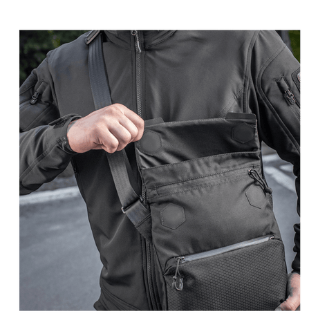 Mann med M-Tac Konvert Taske Elite i Cordura 500D, viser magnetlås for rask tilgang. Vesken har justerbar skulderrem for komfort.