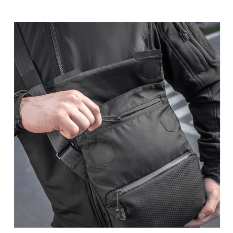 Mann med M-Tac Konvert Taske Elite, laget av holdbar Cordura, med magnetlukking og justerbar skulderrem.