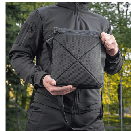 M-Tac Konvert Taske Elite i Cordura 500D og Hex 1000D med tablet-design og justerbar skulderrem, holdt av en person i naturen.