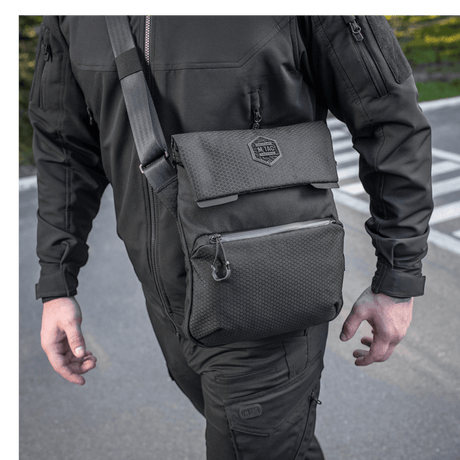 Mann bærer M-Tac Konvert Taske Elite i svart med justerbar skulderrem, laget av slitesterk Cordura 500D og Cordura Hex 1000D.