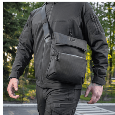 Mann bærer M-Tac Konvert Taske Elite i Cordura-materiale, med justerbar skulderrem og tablet-design, sett utendørs.