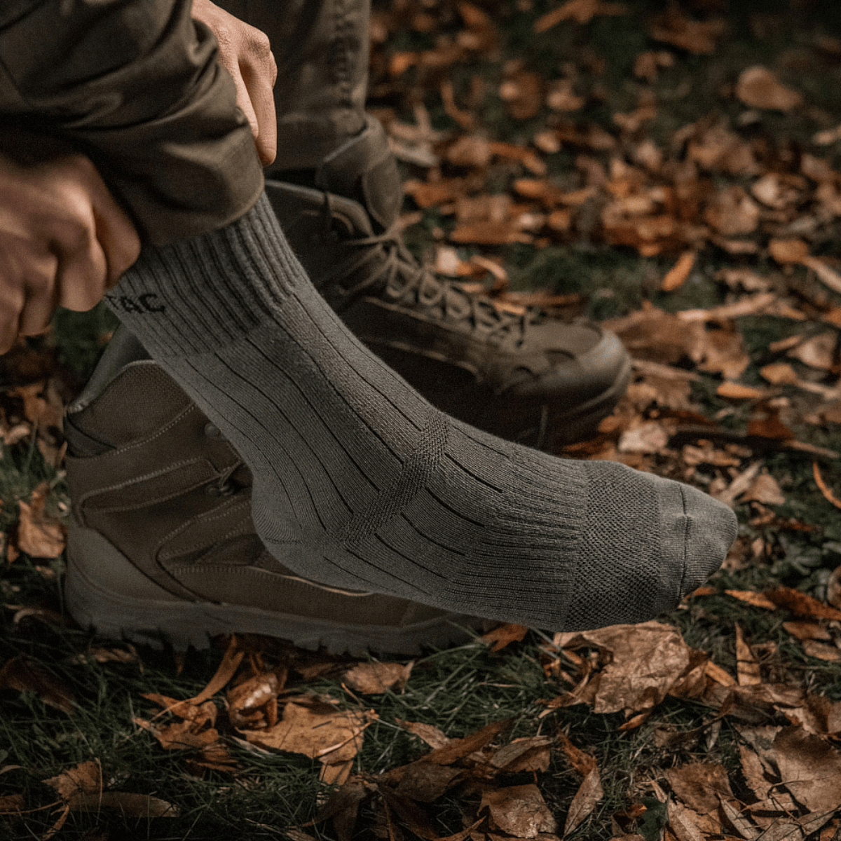 M-Tac Sokker Tactical Army på en mand iført udendørsstøvler, designet til komfort og holdbarhed til både hverdag og ture.