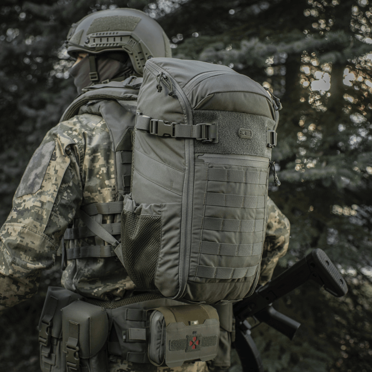 M-Tac Rygsæk Gen. II Elite – Small, militær rygsæk med MOLLE-paneler og mesh-lommer, set i brug i skovmiljø