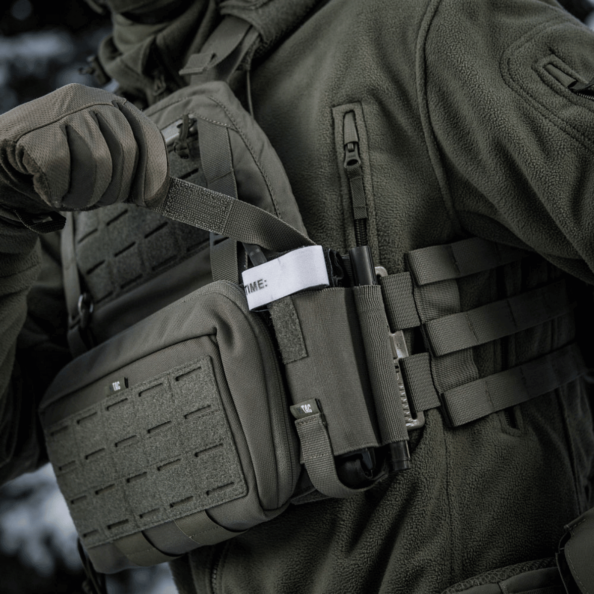 En soldat bærer en M-Tac Elastisk Tourniquet Holder Gen. III i høj kvalitets Cordura 500D, klar til brug i taktisk situation.