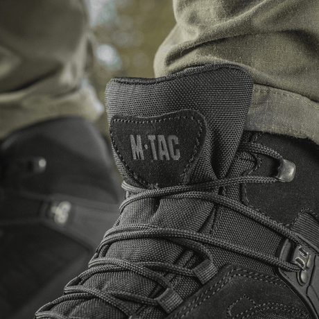 M-Tac taktiske sesongstøvler i svart lær til utendørs bruk, detaljbilde av snørebånd og logo.