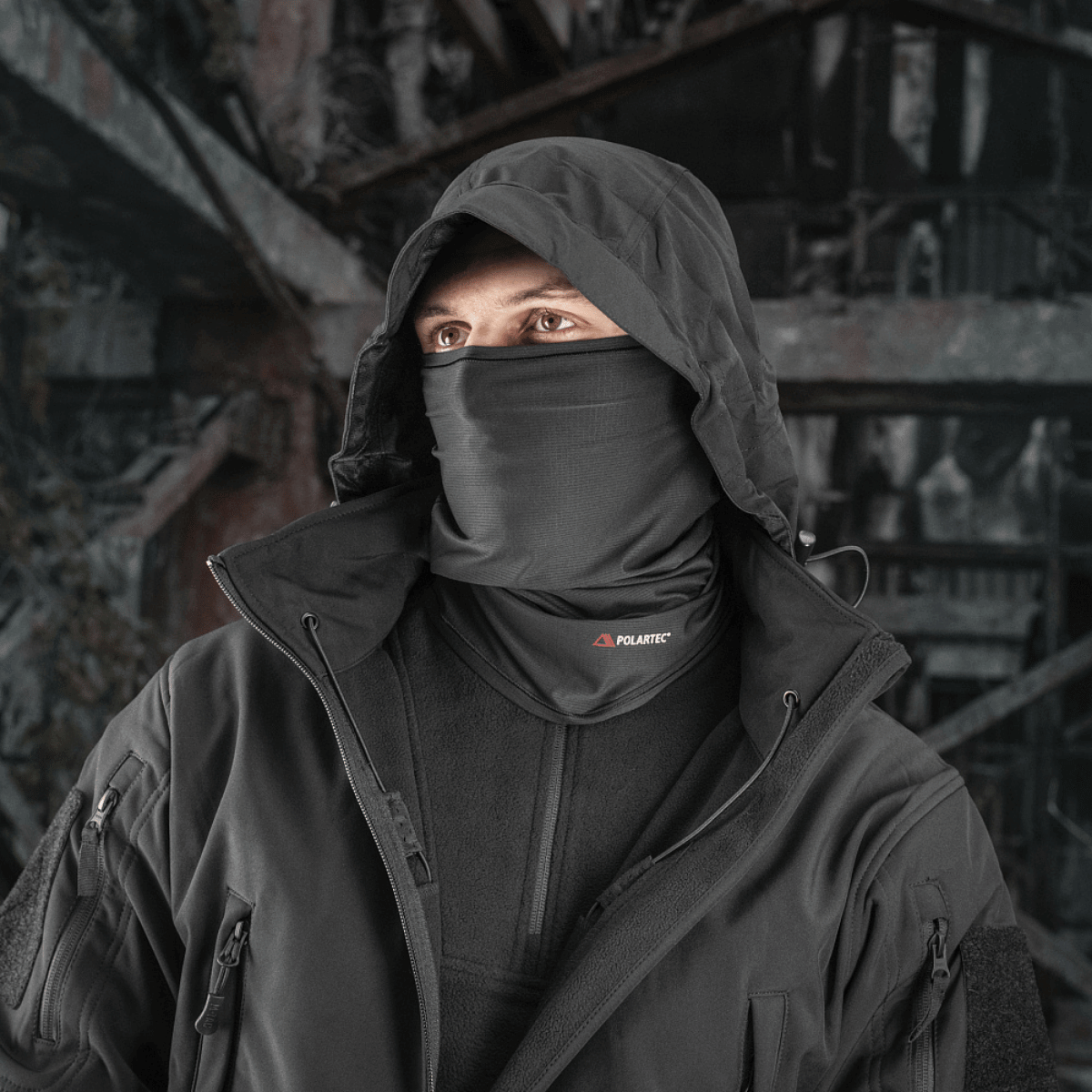 Mand iført M-Tac Polartec Vent Tube Scarf i sort, beskytter mod vind. Alsidigt tilbehør til hals, ansigt i syntetisk Polartec® materiale.