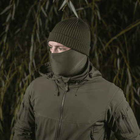 Person iført M-Tac Polartec Vent Tube Scarf i grøn baggrund, der fungerer som ansigtsmaske og beskytter mod vind og kulde.