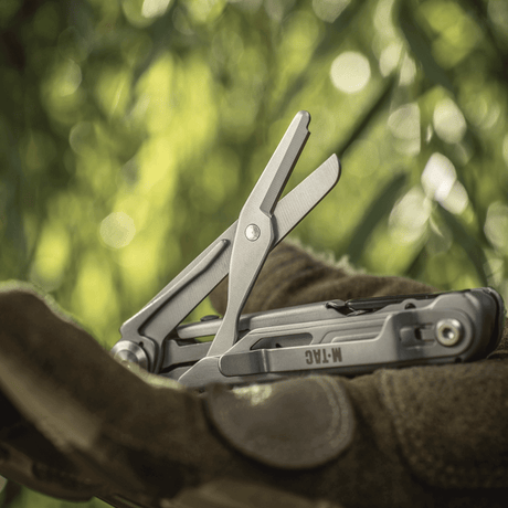 M-Tac Type 3 foldbar kniv (5-i-1) rustfritt stål med verktøyvisning, inkludert saksfunksjon, i naturlig EDC-miljø.