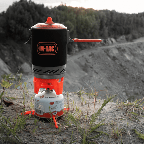 M-Tac gassbrenner med kjele brukt på en klippe, ideell for camping og turer, kompakt og energieffektivt matlagingssystem.