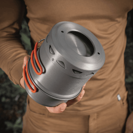 Person holder M-Tac enkelt kokesett til brenner i anodisert aluminium, egnet for camping og friluftsliv.