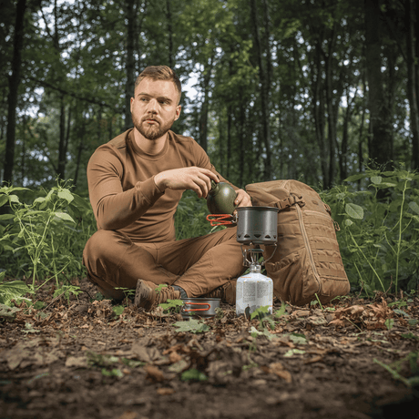 Mann i skogen bruker M-Tac enkelt kokesett til brenner for camping, sitter ved komfyr med ryggsekk.