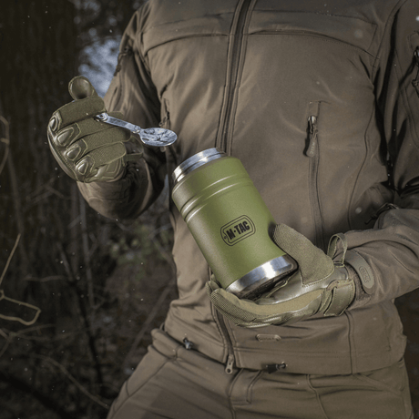 M-Tac Termoflaske 750 ml med sammenleggbar skje brukt utendørs, vist med moderne design og praktisk skje, passer for camping og fotturer.