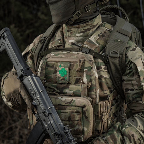 Militærklær med M-Tac Patch Lucky Card (broderi) med kløverblad, festet med Velcro til kamuflert ryggsekk.