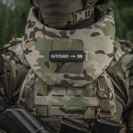 M-Tac Patch Autosave PVC i camo, montert på militærvest for fokus og dedikasjon, med Velcro-bakside for enkel festing.