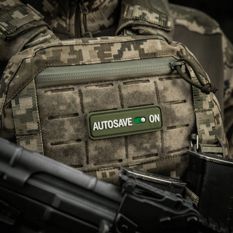 M-Tac Patch Autosave PVC i 3D på taktisk vest, viser detalj i camouflage-look og enkel festing, 8x2.5 cm, fullfarge.