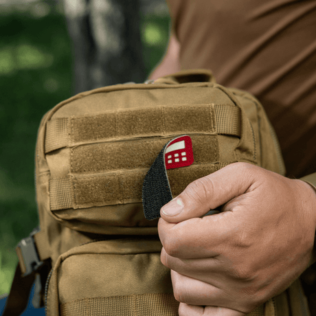M-Tac Patch Flag 25x80 Mini Squares på en veske, holdt av en person. Cordura 500D, velcro-montering, laser cut, slitesterk og lett patch.