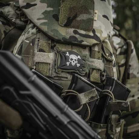M-Tac Patch Jolly Roger PVC på taktisk utstyr med kamuflasje, symboliserer eventyrlyst og besluttsomhet.