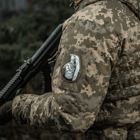 Militærentusiast i uniform med M-Tac Patch M67 Granat 3D PVC på ermet, viser amerikansk M67-granat med emoji og teksten "Born to Kill".