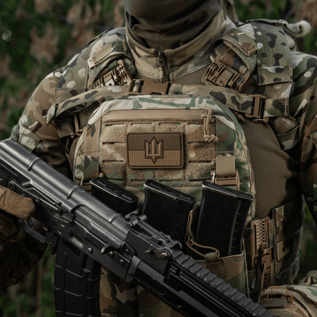 Soldat iført kamuflasjevest med M-Tac patch Ukraine Flag med ZSU Trident PVC, holder gevær, symboliserer ukrainsk stolthet og arv
