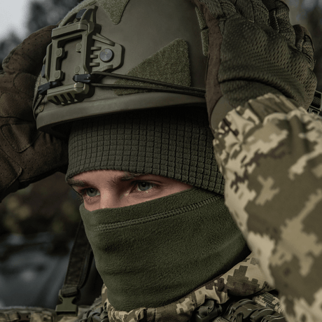 Person iført M-Tac Rip-Stop Fleece Hjelmliner og militær hjelm i koldt vejr