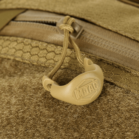 Detalj av M-Tac Sling Pistolveske Elite Hex med Velcro, viser glidelås og håndtak med logo, laget av slitesterkt Cordura-materiale.