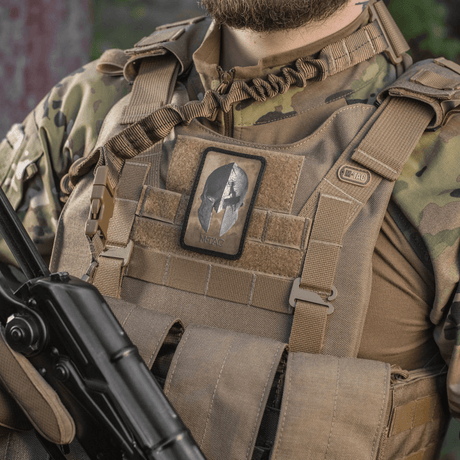 M-Tac Spartan Hjelm Patch festet til taktisk vest, symboliserer mot og styrke, vintage design i slitesterk Cordura 500D.