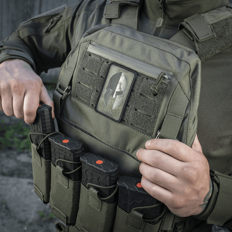 Mann iført M-Tac Spartan Hjelm Patch, Cordura 500D, på militærvest, viser mot og styrke med velcro-festing, vintage look.