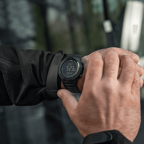 M-Tac Tactical Ur 2147 på håndleddet i naturen, robust design for utendørs og taktisk bruk med funksjoner som kompass og LED-belysning.