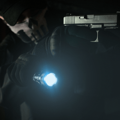 Taktisk bruk av M-Tac lommelykt P4 med sterkt LED-lys og pistol i en mørk setting.