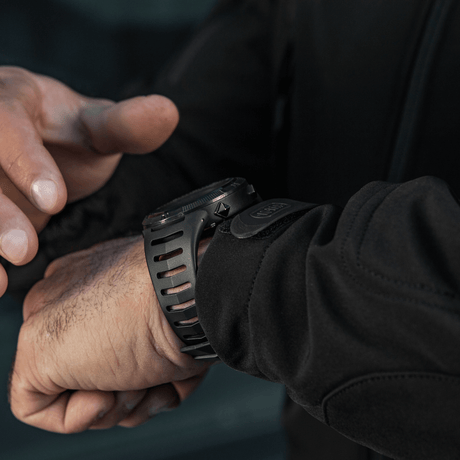 Person justerer M-Tac Tactical Ur 2147 på håndleddet. Ideell for utendørs og taktisk bruk med robust design og praktiske funksjoner.