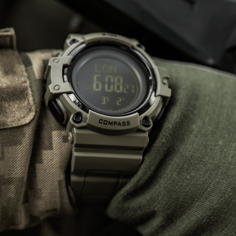 M-Tac Tactical Ur med Kompass 2233 på kamuflasjeerm, robust design med LED-bakgrunnsbelysning og kompass, ideell for utendørs og taktisk bruk.