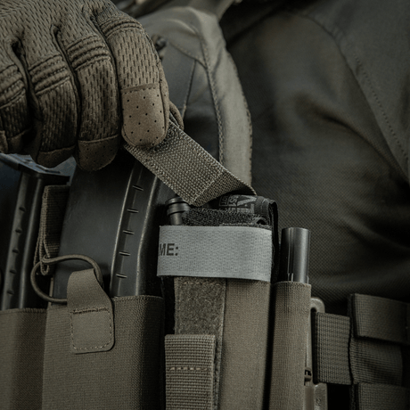 M‑Tac Tourniquet Pouch Elastic Gen.5 festet på taktisk utstyr, viser rask tilgang til tourniquet med elastisk velcrobånd.