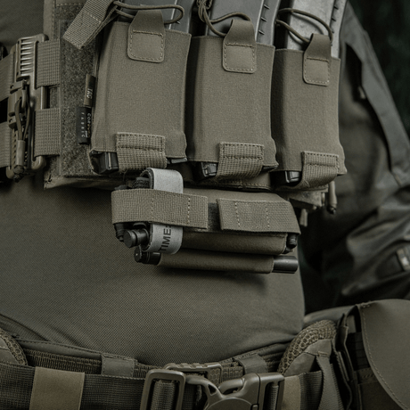 M-Tac Tourniquet Pouch Elastic Gen.5 festet på taktisk utstyr, laget av Cordura 500D, med elastisk bånd for rask tilgang.