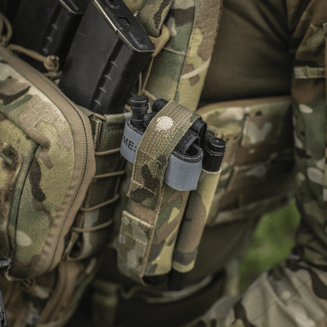 Taktisk utstyr med M‑Tac Tourniquet Pouch Elastic Gen.5, festet til uniform med CAT tourniquet, kamuflasjemønster.