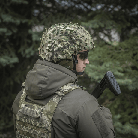Soldat iført M‑Tac Vilha Hjelmcover Elite i MULTICAM-camouflage for beskyttelse og skjul i naturen, designet for FAST hjelmer.