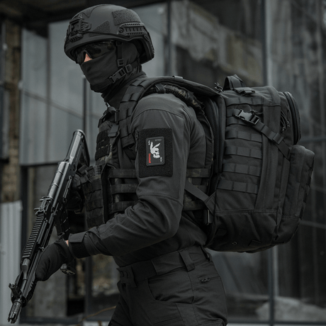 Taktisk operatør iført "M-Tac Patch Bad Boy (broderi)" med kaninkranium på ace of spades-kort, holder våpen, i urban miljø.