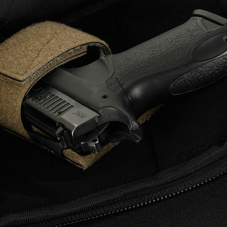 Nærbilde av en pistol i en M-Tac Sphaera Hardsling Bag Large Elite med Velcro, laget av robust Cordura-stoff med Velcro-festning.