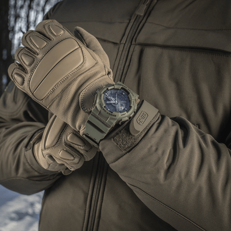 M‑Tac Sport-klokke med robust design, perfekt for friluftsaktiviteter, vist på arm med hansker i vinternatur.