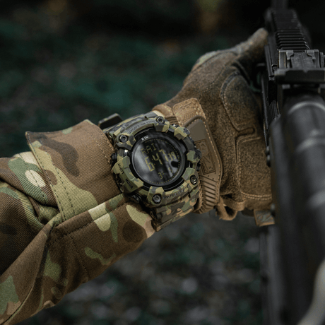 M-Tac Tactical Ur 2037 på håndleddet med camotøy, ideell for utendørs og taktisk bruk, fremhever robust design og funksjonalitet.