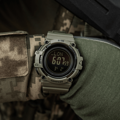 M-Tac Tactical Ur med Kompass 2233 båret av person i kamuflasje, egnet for utendørs aktiviteter med LED-belysning og stoppur.