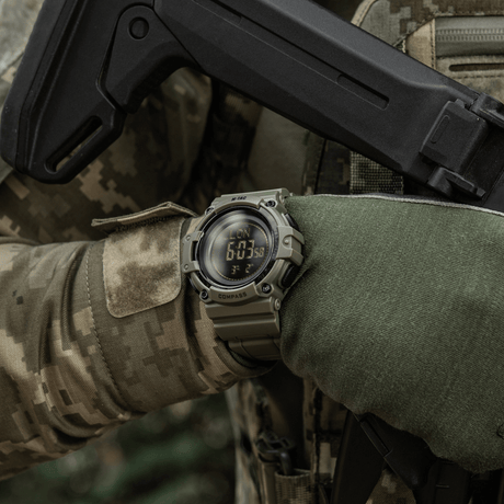 M-Tac Tactical Ur med Kompass 2233 i bruk i utendørs taktisk scenario, viser robusthet og funksjonalitet med kompass og LED-bakgrunnsbelysning.