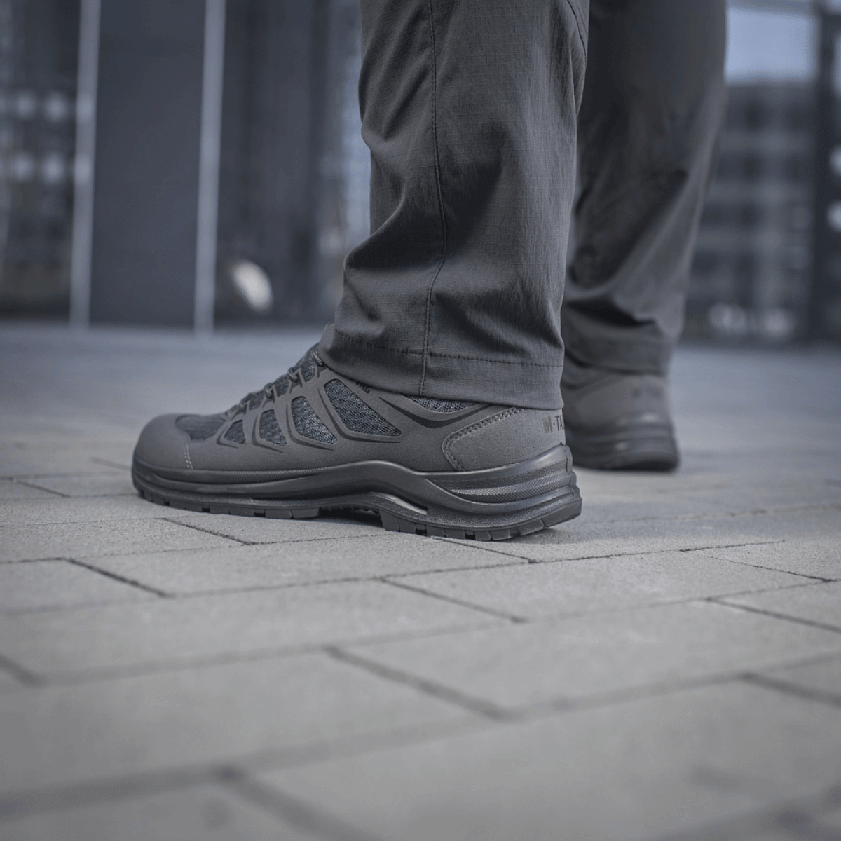 Mand iført M-Tac Bukser Sahara Flex Light på gade, viser fleksibilitet og stilfuldt design. Slidstærk og velegnet til sommerbrug.