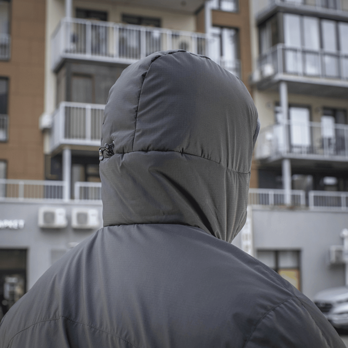 M-Tac Paladin Jakke i grå farve, designet til daglig brug, bagfra med bygninger i baggrunden.