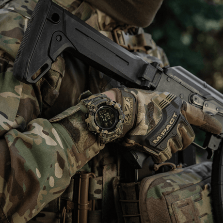 M-Tac Tactical Ur 2037 bæres av en person i camo med taktisk utstyr og skytevåpen.