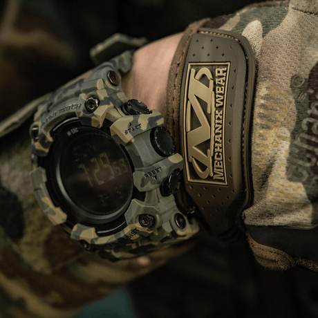M-Tac Tactical Ur 2037 med robust design, perfekt for utendørs og taktiske aktiviteter, vist på camotøy mot en naturfarget bakgrunn.