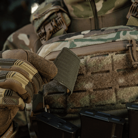 Soldat i kamuflasje holder M-Tac Patch Ukraine-flagg med våpenskjold med Velcro på utstyr.