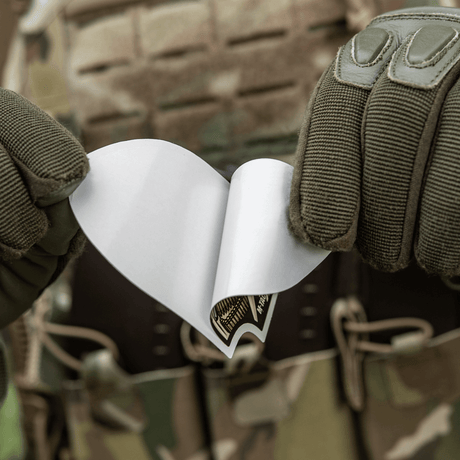 M-Tac Sticker Valkyrie holdt av person i kamuflasje, klar til bruk. Viser den beslutsomme krigsgudinnen med M4-gevær på Arrowhead-patch.